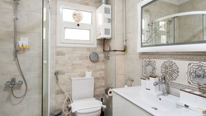 Une salle de bain équipée d’une douche, de toilettes, d’un lavabo et d’un grand miroir.