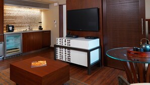 Una cocina moderna con horno integrado, cafetera y televisor de pantalla plana montado en la pared.