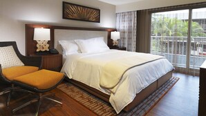 Habitación de hotel con una cama grande, una silla, una mesita de noche y vistas al exterior.