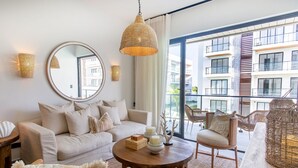 Un salon moderne avec un canapé, des fauteuils, une table basse ronde et un grand miroir.