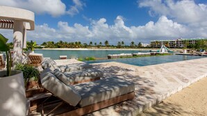 Un espace aménagé au bord de la piscine, avec des chaises longues et une vue sur la plage et l’océan.