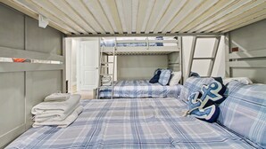 A compact room with bunk beds, a door, and a stack of towels. - New Lakefront Estate | Sleeps 34 | Private Dock (LaFollette)
