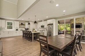 A spacious kitchen with white cabinets, a central island, and a dining area with wooden chairs.