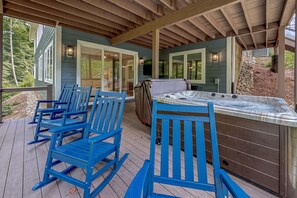 Eine überdachte Terrasse im Freien mit blauen Schaukelstühlen und einem Whirlpool.