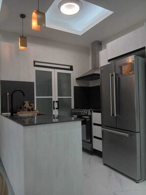 A modern kitchen with a central island, stainless steel appliances, and pendant lighting. - Cozy 2-bedroom condo with AC and Pool in beautiful Santo Domingo (Santo Domingo)