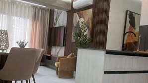 Un soggiorno moderno con un'isola centrale, un'area pranzo con sedie e un'ampia finestra con tende.