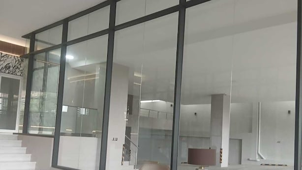 Un interno spazioso e moderno con ampie vetrate, pavimento lucido e arredi contemporanei.