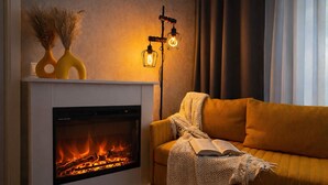 Ein modernes Wohnzimmer mit Kamin, einer Couch und einer Lampe.