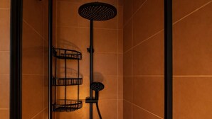Ein Badezimmer mit einem schwarzen Handtuchhalter, einer schwarzen Duschbrause und einer schwarzen Stehlampe.