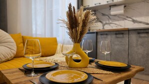Ein Esstisch, gedeckt mit gelben Tellern, Weingläsern und einer gelben Vase mit getrockneten Pflanzen.