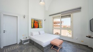 Ein Schlafzimmer mit Bett, einer Bank, einem Gemälde und einem Fenster.