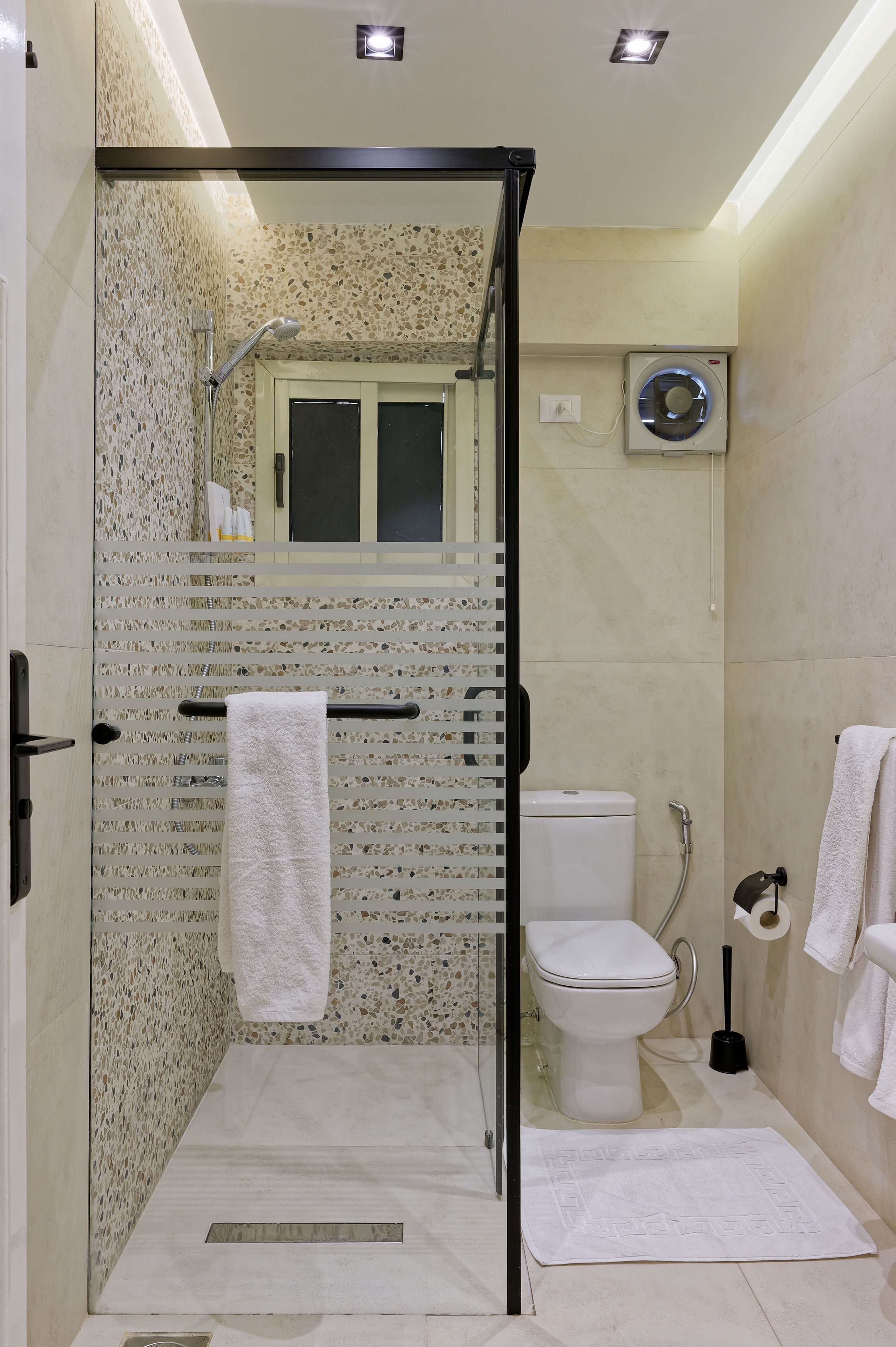 A modern bathroom with a glass-enclosed shower, a toilet, and a built-in air conditioning unit.