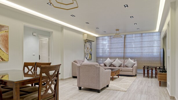 A modern living room with a sofa, chairs, a coffee table, and a dining table. - VESTA - Luxury APT - 2BR - Heliopolis (Al Golf)