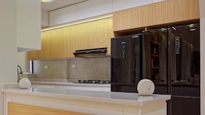 Cozinha moderna com ilha central, eletrodomésticos de aço inoxidável e iluminação pendente.