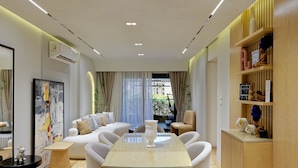Uma sala de estar moderna com uma mesa de jantar de vidro, assentos confortáveis e vista para o exterior.