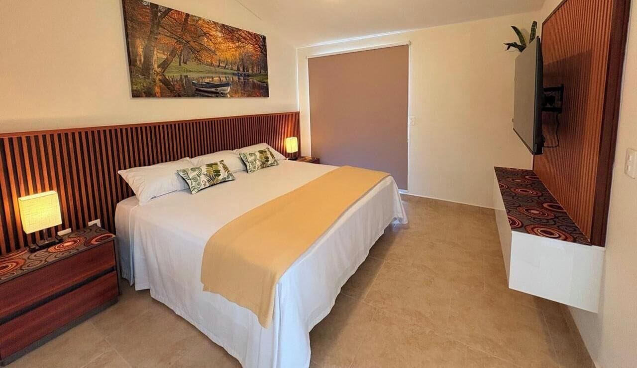 Ein Hotelzimmer mit einem Bett, Nachttischen, einem Fernseher und einem Gemälde an der Wand.
