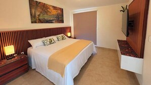 Quarto de hotel com uma cama, mesas de cabeceira, uma televisão e um quadro na parede.