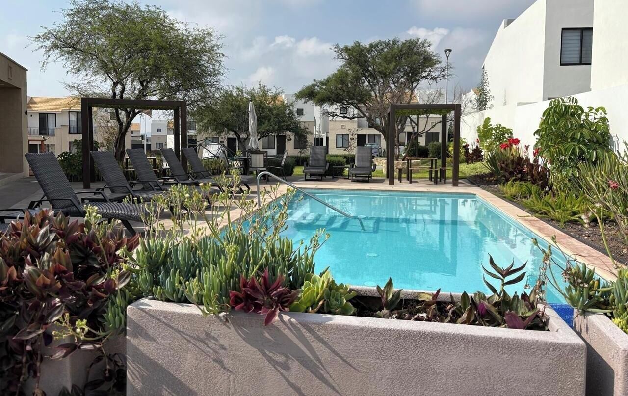 Un espace piscine sur le toit, avec des chaises longues et une pergola.