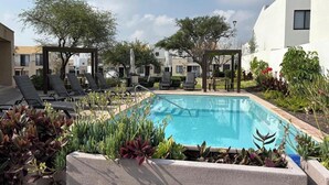 Uma área de piscina no terraço com espreguiçadeiras e um pergolado.