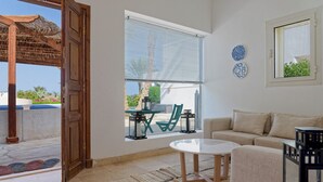 Una sala moderna con sofá, una mesa de centro y un ventanal con persianas.