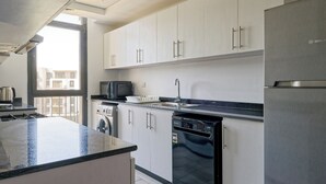 Een moderne keuken met witte kastjes, een roestvrijstalen koelkast, een vaatwasser en een magnetron.