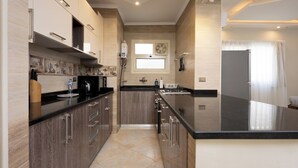 Une cuisine moderne avec des meubles de couleur bois foncé, un plan de travail noir et un grand îlot central.