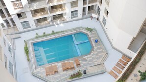 Une piscine sur le toit, avec des chaises longues et un petit espace aménagé en jardin.