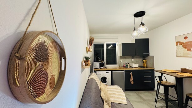 Et moderne køkken med spiseplads, en sofa og en hængende vævet kurv.