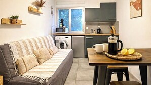 En kompakt bolig med sofa, spisebord, kaffemaskine og vaskemaskine.