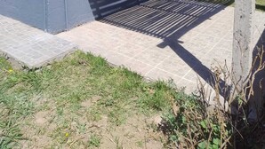 A modern building with a grey exterior, a covered garage with a metal roof, and a paved driveway. - Rincon de Olivares, Alta Gracia, Cordoba - Tranquility and Family (Villa del Prado)