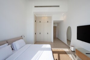 Una camera da letto moderna con un letto grande, un armadio, una televisione e uno specchio.