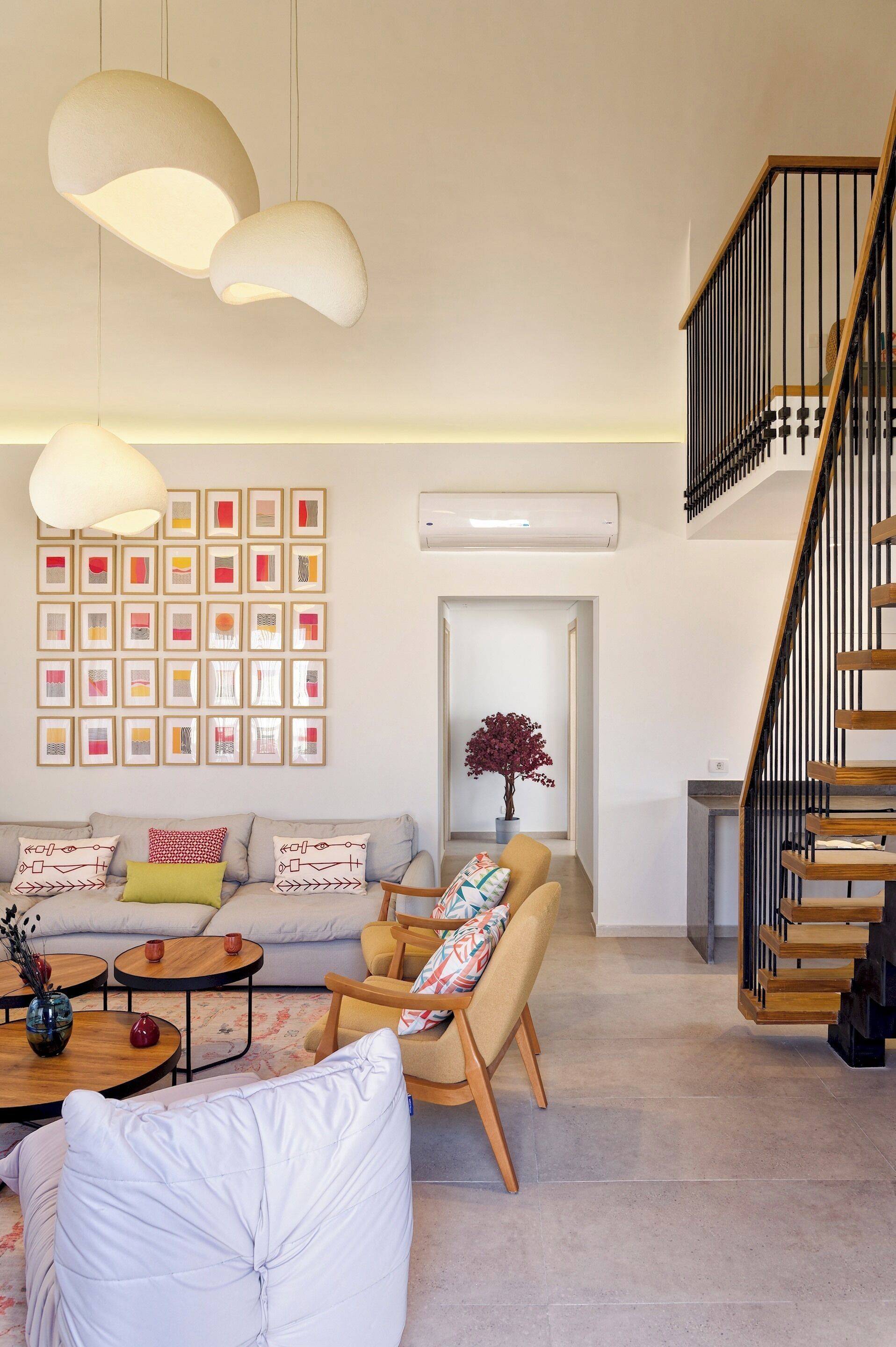 A modern living room with a sofa, armchairs, a coffee table, and a staircase.