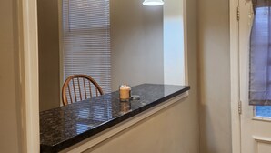 A bathroom with a marble countertop, a mirror, two pendant lights, and a door with a window. - 2-bedroom townhome in superb Baltimore with parking and gated yard (Baltimore)