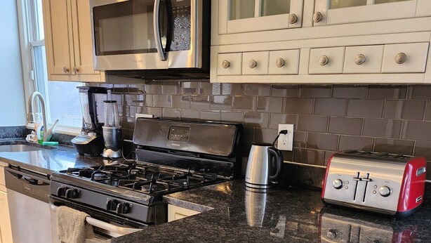 A kitchen with a granite countertop, stainless steel appliances, and white cabinetry. - 2-bedroom townhome in superb Baltimore with parking and gated yard (Baltimore)