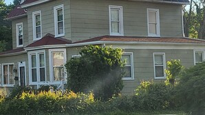 A two-story house with a symmetrical facade, a central entrance with a porch, and a well-maintained front yard. - 2-bedroom townhome in superb Baltimore with parking and gated yard (Baltimore)
