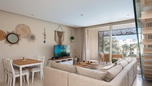 A modern living room with a sofa, dining table, and TV. - VESTA - Luxury APT - 2BR - Mangrovy (El Gouna)