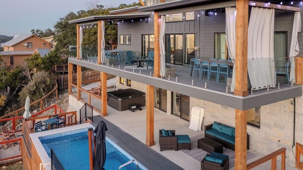 Un edificio de dos pisos con piscina, asientos exteriores y un patio cubierto.