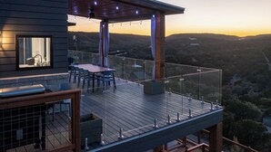 Una terraza de madera con una mesa y sillas, con vista a un paisaje montañoso.