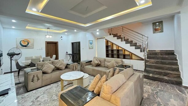 Una sala de estar moderna con un sofá, una mesa de centro y una escalera que lleva a un nivel superior.