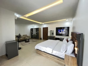 Quarto moderno com uma cama grande, uma televisão e uma escrivaninha.