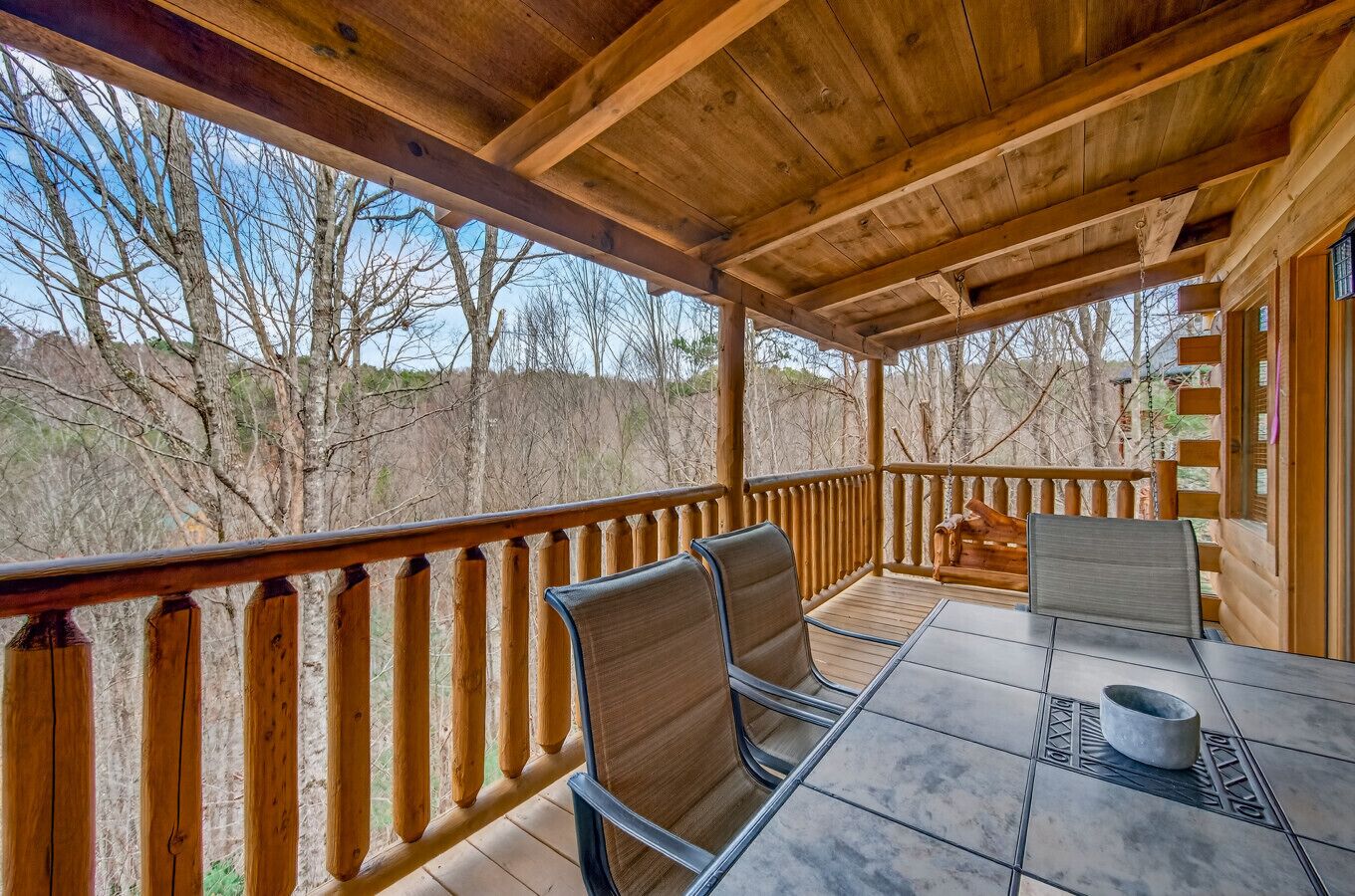 A covered outdoor seating area with wooden railings and a table with chairs.