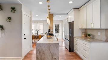 A modern kitchen with marble countertops, white cabinetry, and a central island.