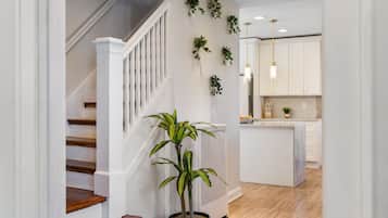 A modern interior with a staircase, potted plants, and a kitchen area.