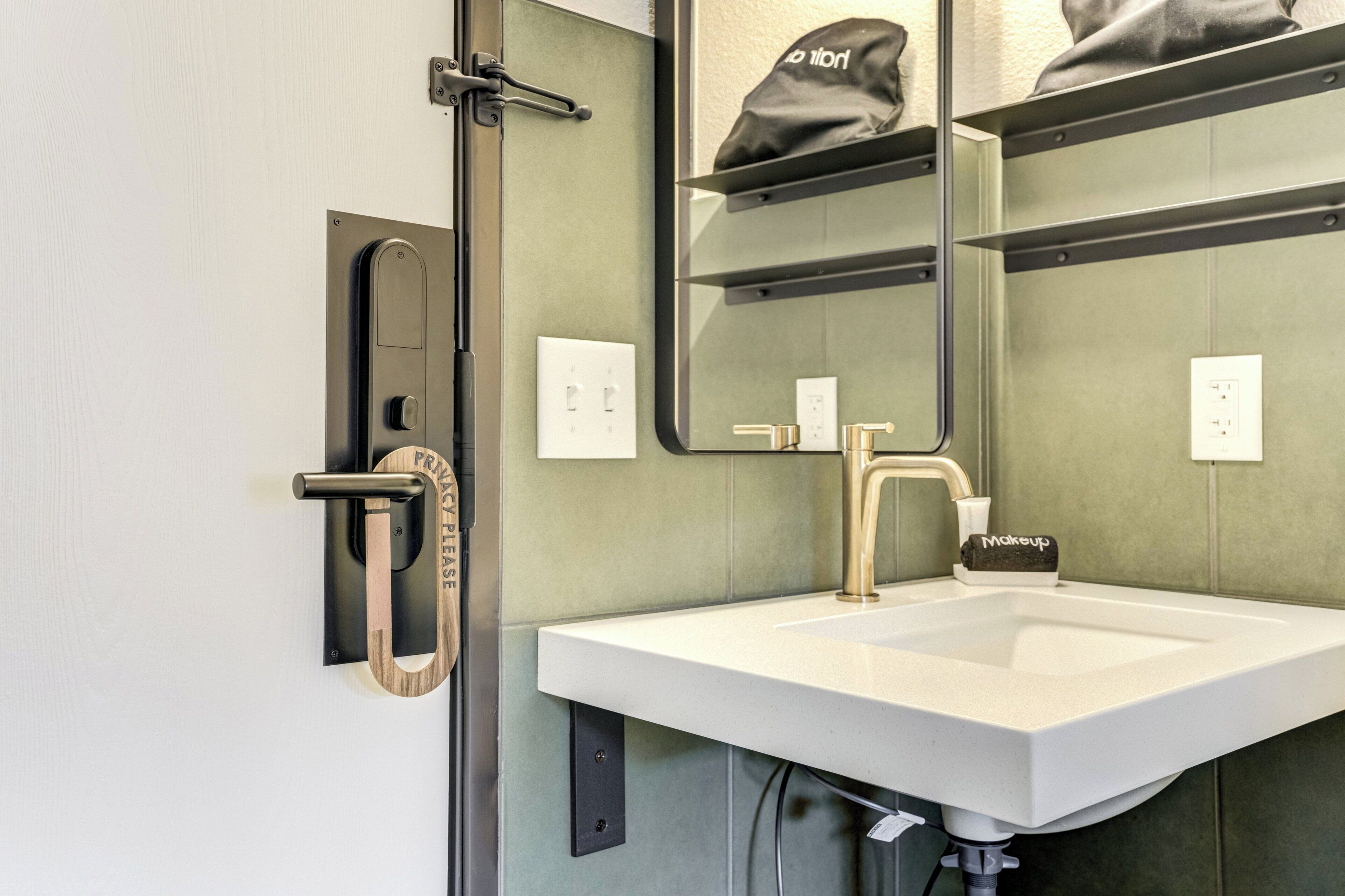 A bathroom with a white sink, a mirror, a towel rack, and a door with a towel holder.
