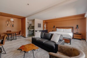 A modern hotel room with a bed, a sofa, a dining table, and a small kitchen area. - The Outrider Hotel (Manitou Springs)