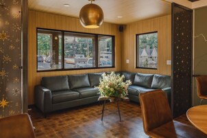 Un interior moderno con un sofá de cuero, una mesa de centro de madera y grandes ventanales que dan a la calle.