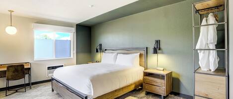 A bedroom with a bed, bedside tables, a desk, a chair, a wardrobe, and a window.