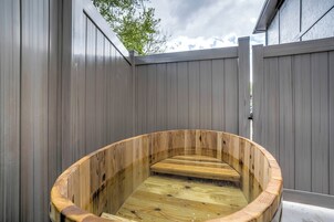 A wooden hot tub in a fenced outdoor area.