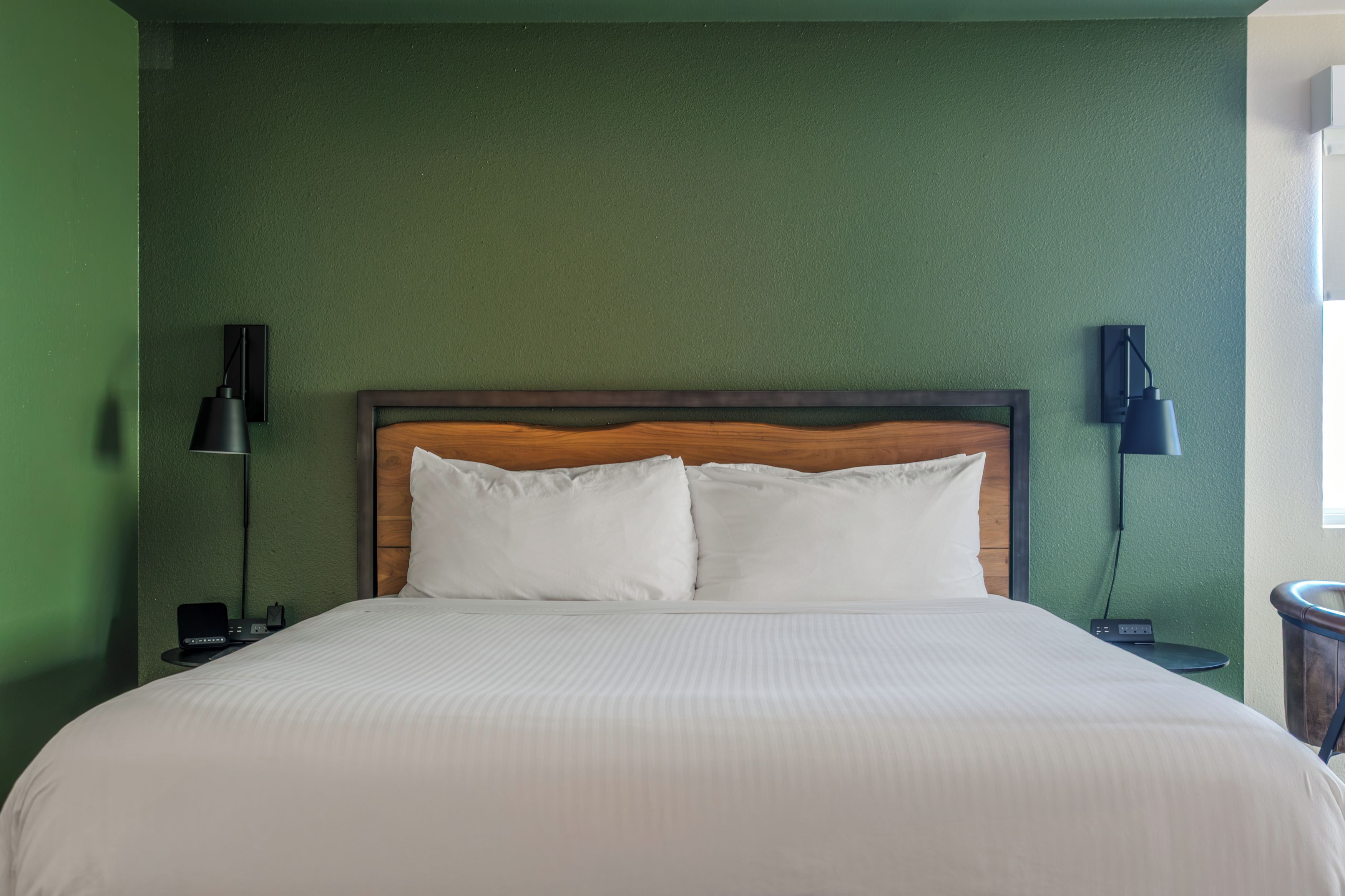Ein Hotelzimmer mit einem Bett, zwei Nachttischlampen und einer grünen Wand.