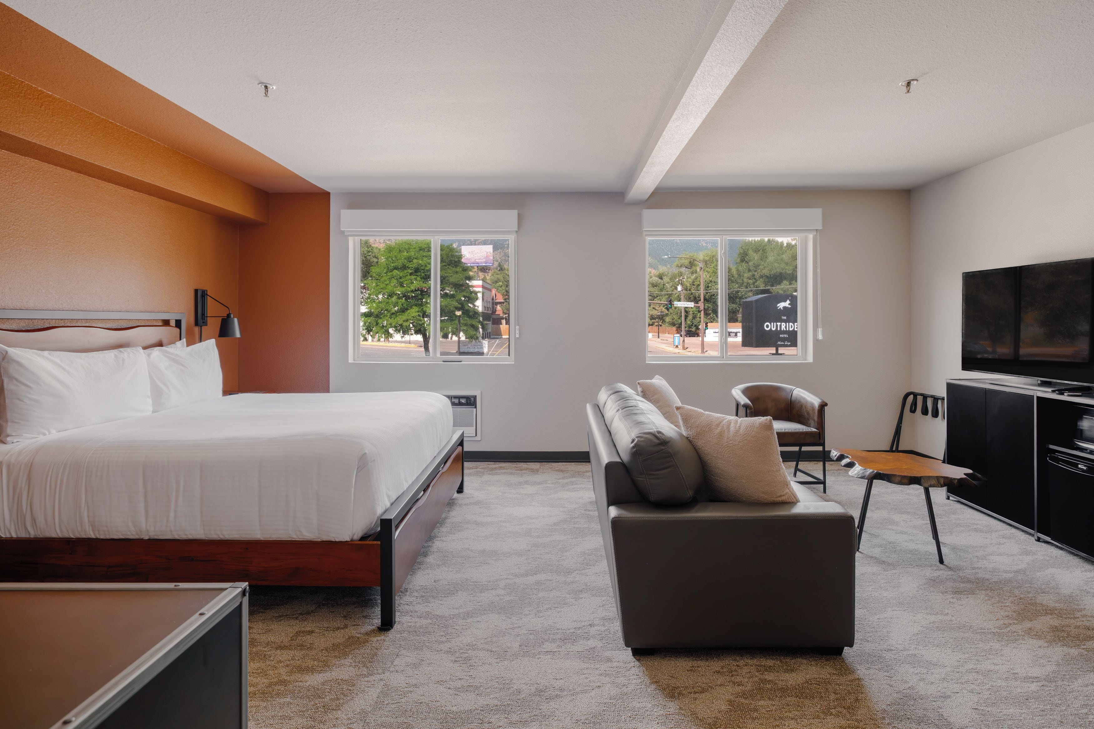 A hotel room with a bed, a sofa, a TV, and a desk.